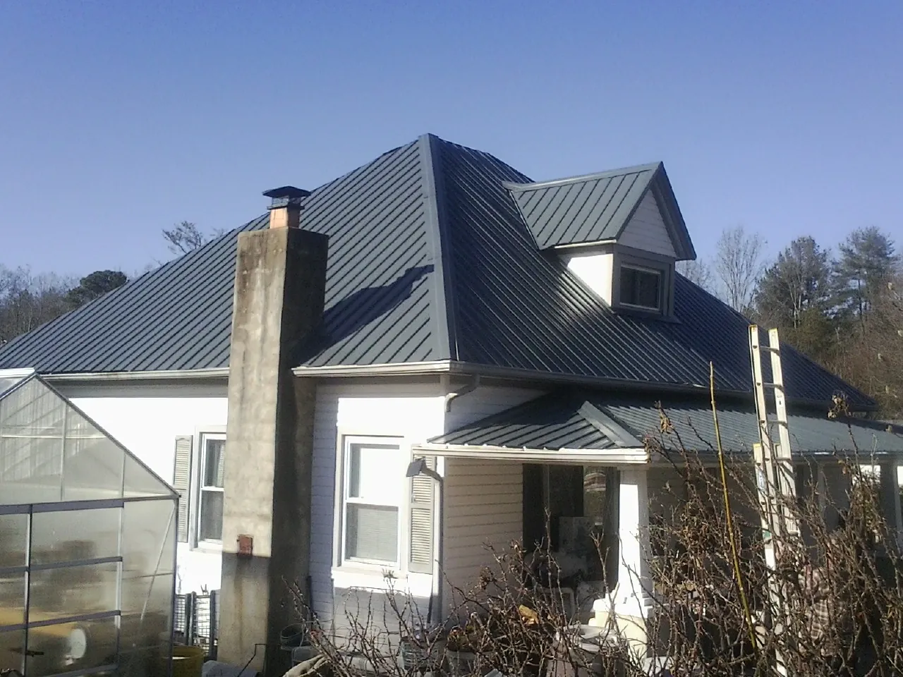 Dark blue standing seam metal roof on a white farmhouse with dormer — Slate & Tile Roof Repair by Roofing Brothers in Frenchville