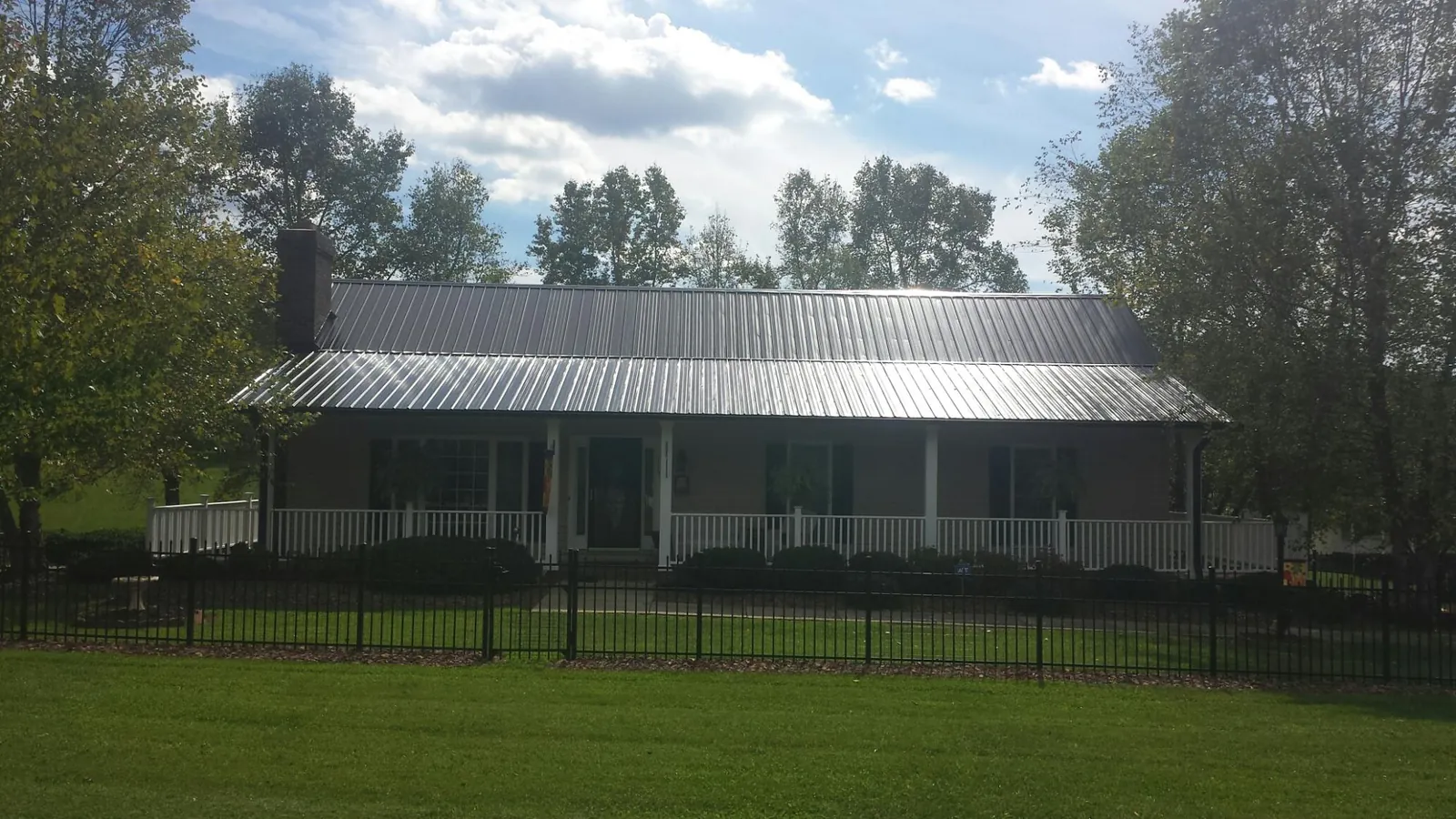 Gray metal roof on a brick ranch with a full width front porch — Gutter Guard Installation work by our crew in Frenchville