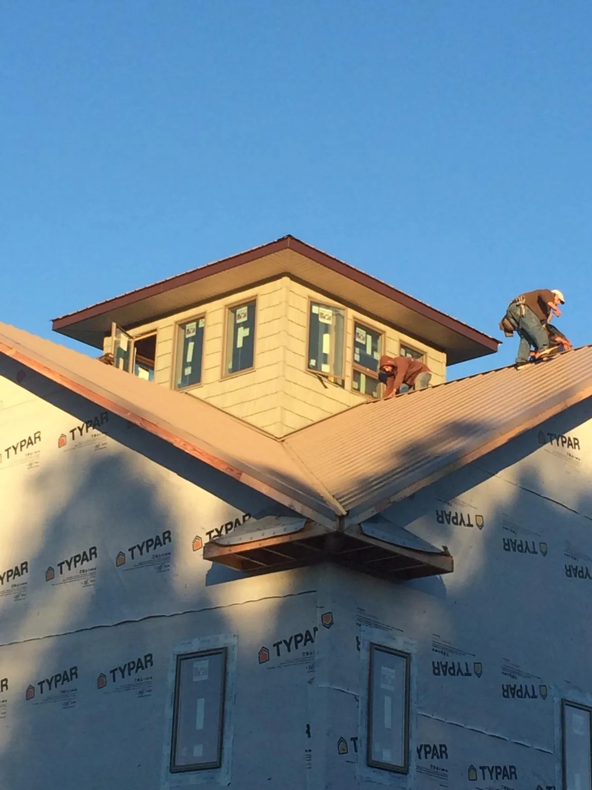 Roofers working around a rooftop cupola on a new metal roof at sunset — Roof Waterproofing in Frenchville by Roofing Brothers
